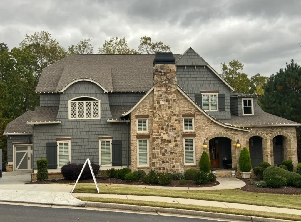 Daytime exterior of a stone residential home for roofline and landscape holiday lighting planning.
